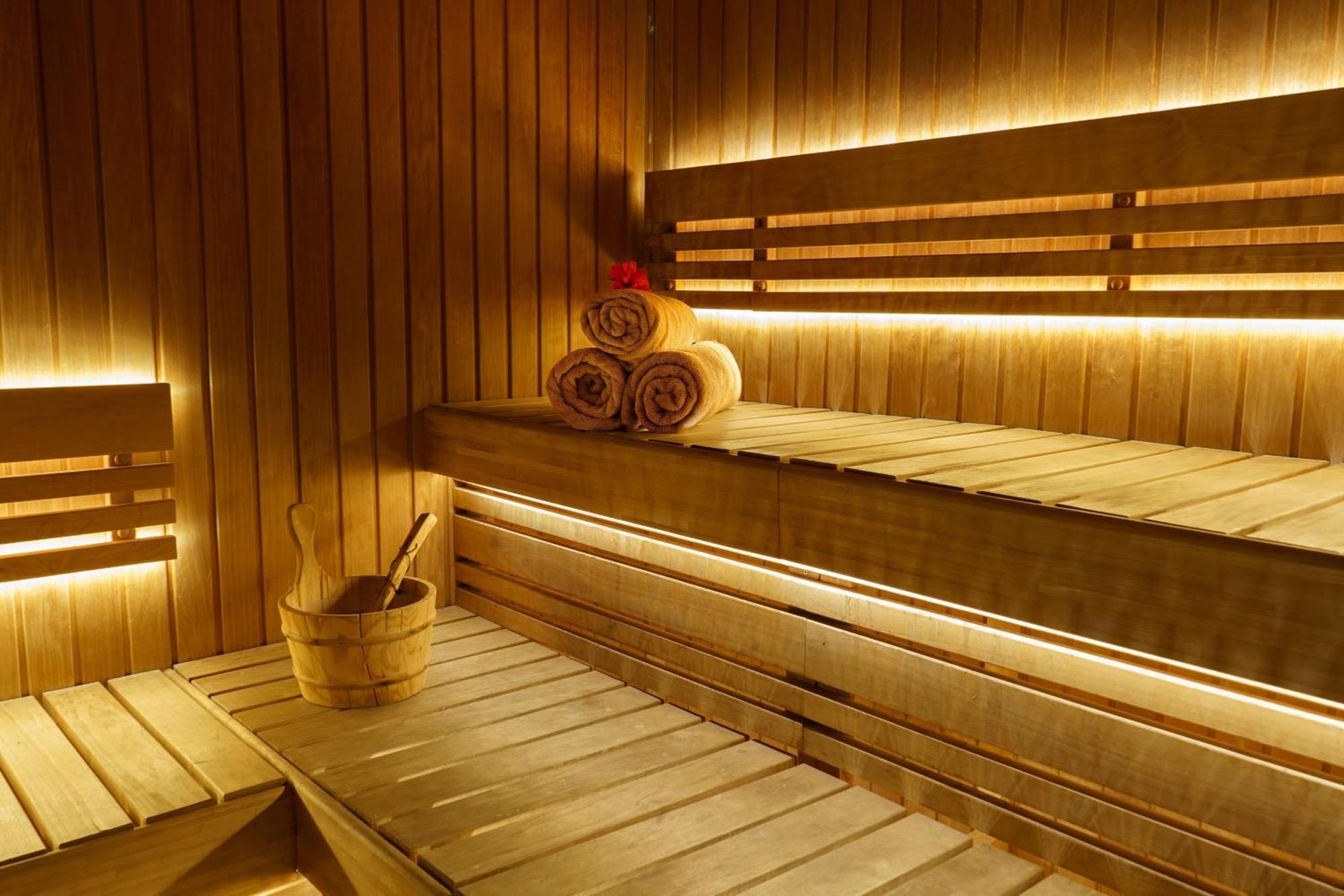 Sheraton Abu Dhabi Hotel & Resort Exterior photo The photo depicts a wooden sauna interior. The walls and benches are made of wood, creating a warm and natural atmosphere. There are three rolled towels placed neatly on a bench, and a small wooden bucket with a ladle is situated nearby, likely for p